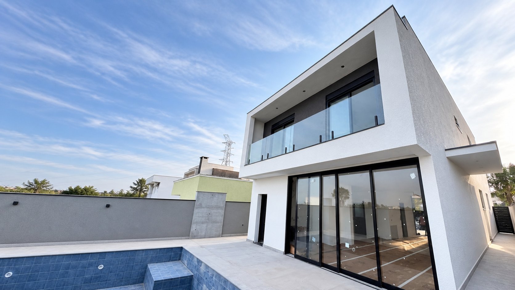 Fachada residencial com guarda-corpo de vidro, janelas integradas e portas de correr com perfis pretos
