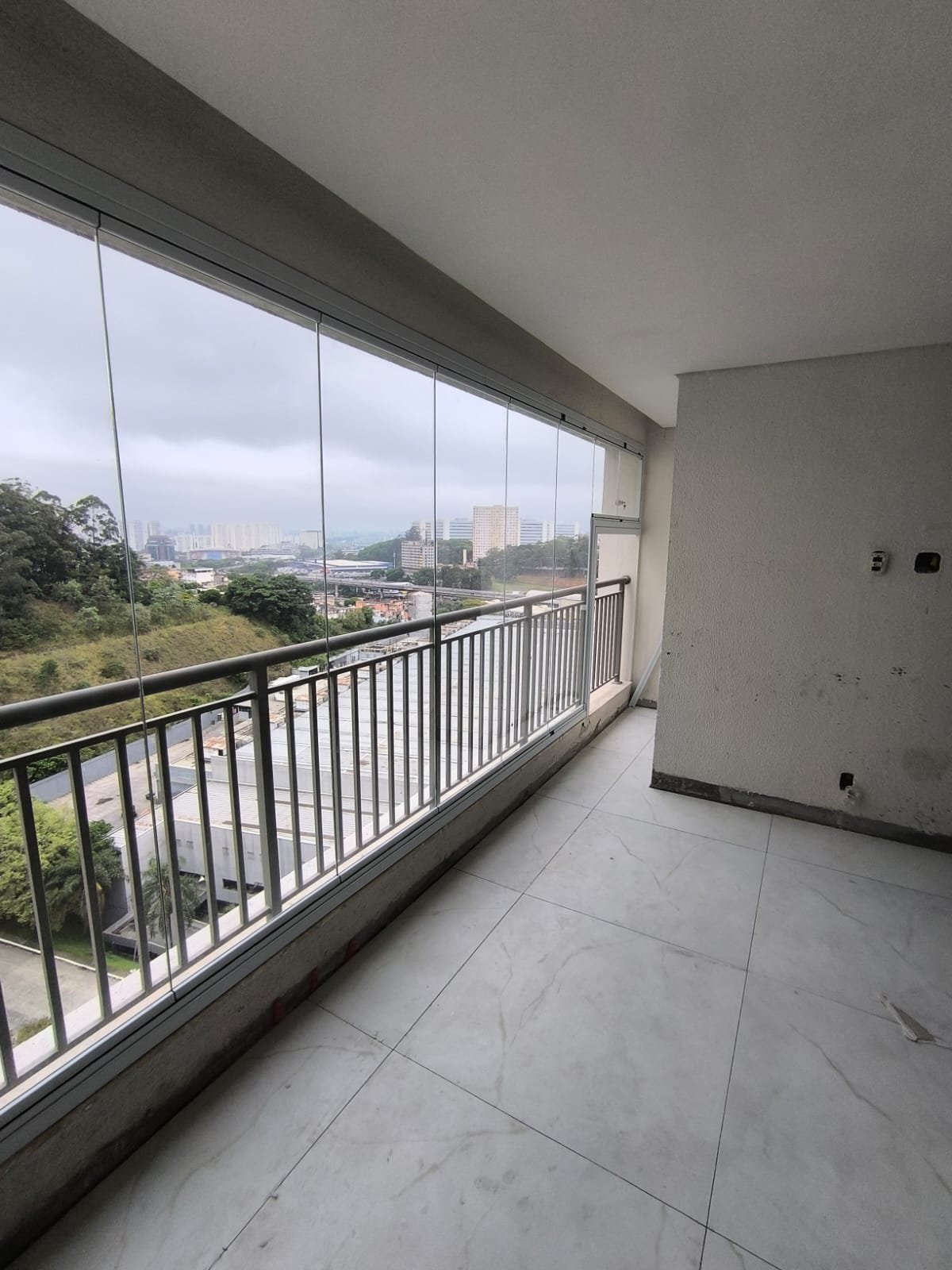 Vista lateral de sacada envidraçada com perfis brancos acompanhando o guarda-corpo